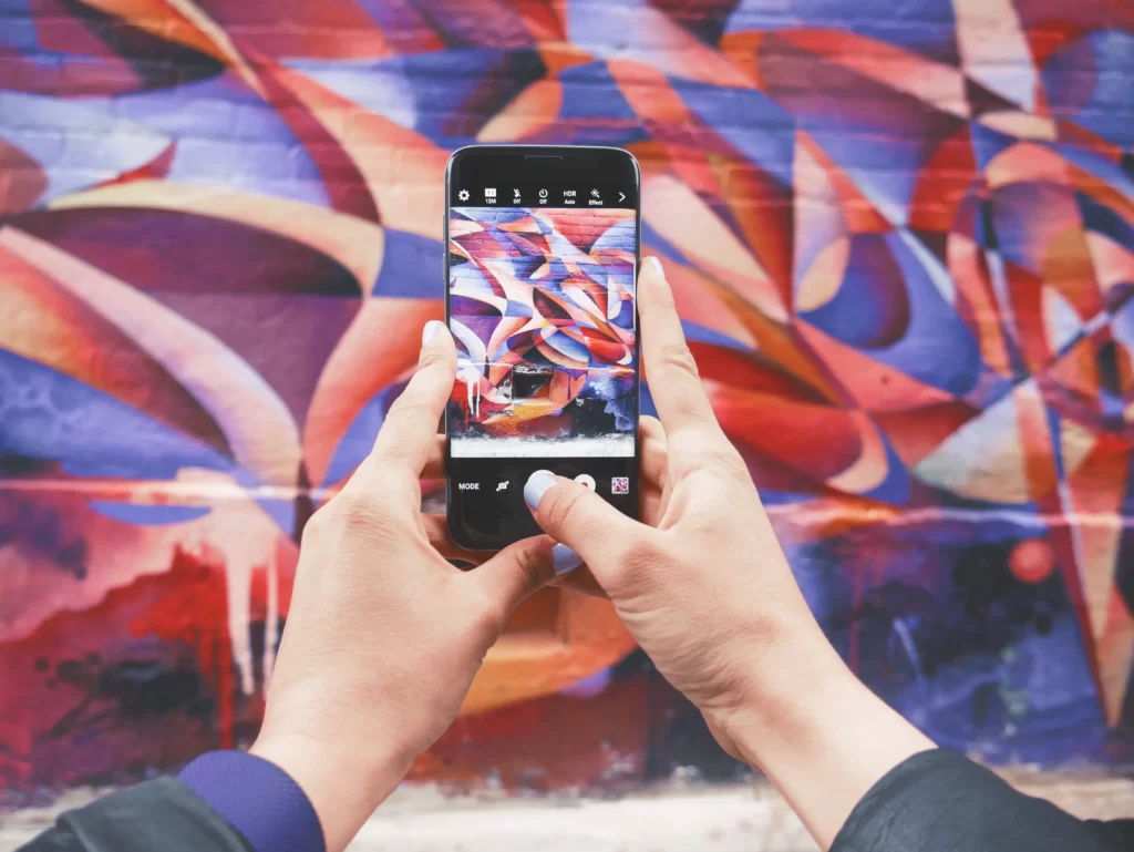 homem tirando foto de um mural para documentar o seu cotidiano e postar nas redes sociais